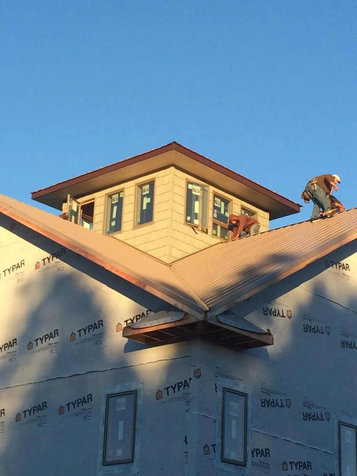 Roofers working around a rooftop cupola on a new metal roof at sunset — Roof Waterproofing in Waterville by Roofing Brothers